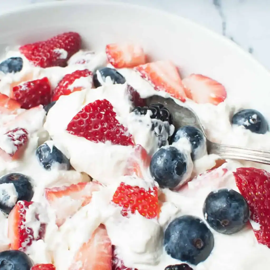 Triple berry cheesecake fruit salad with strawberries, blueberries, and creamy filling in a bowl